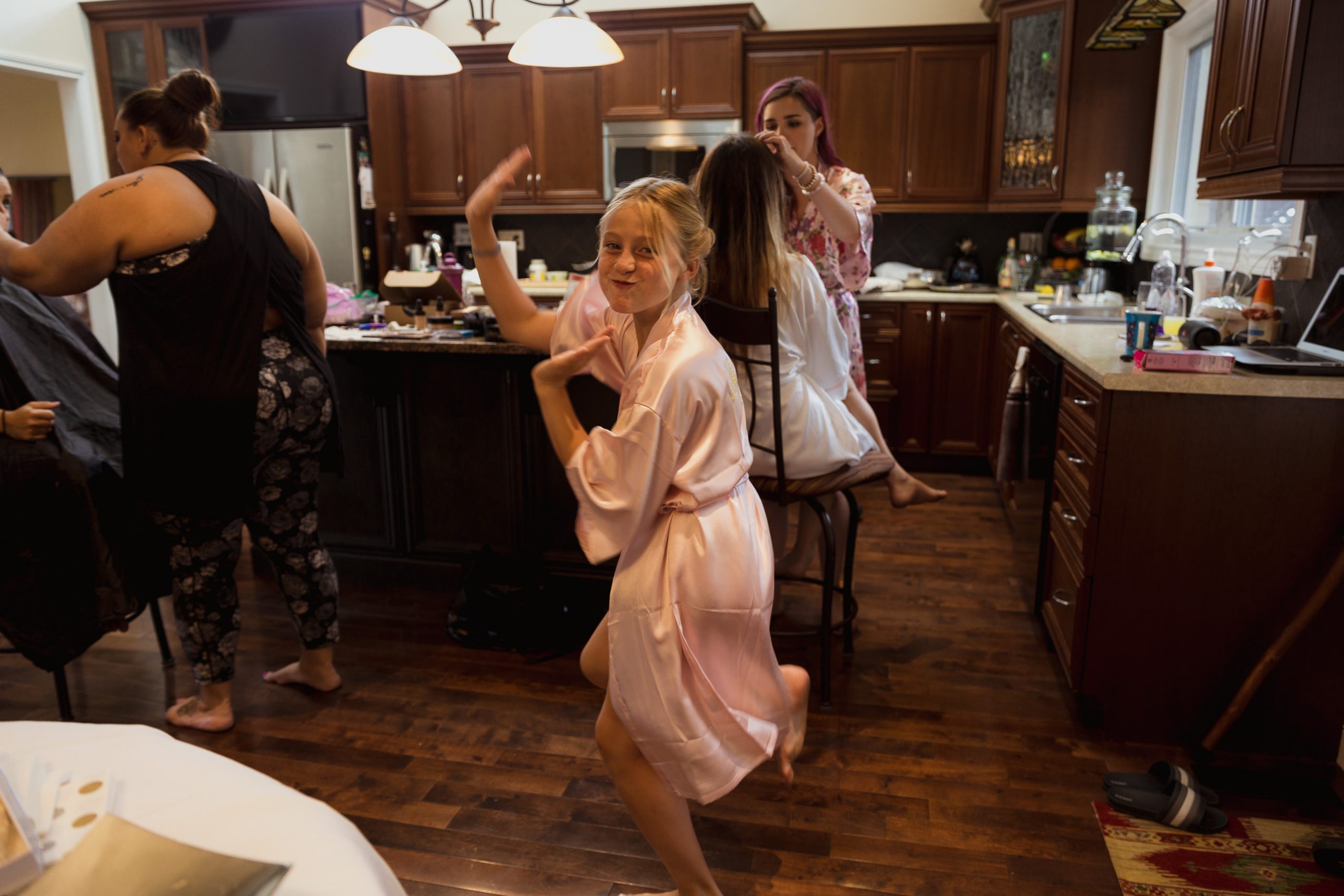 Wedding photos girls getting ready flower girl dancing in the kitchen in her bridesmaid robe