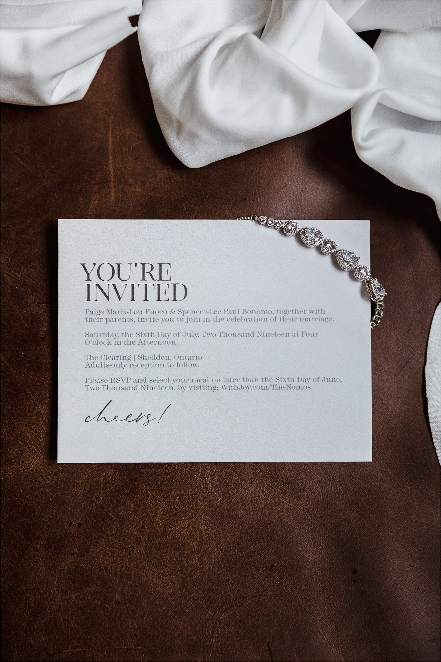 Wedding invitation and bride's bracelet on leather couch