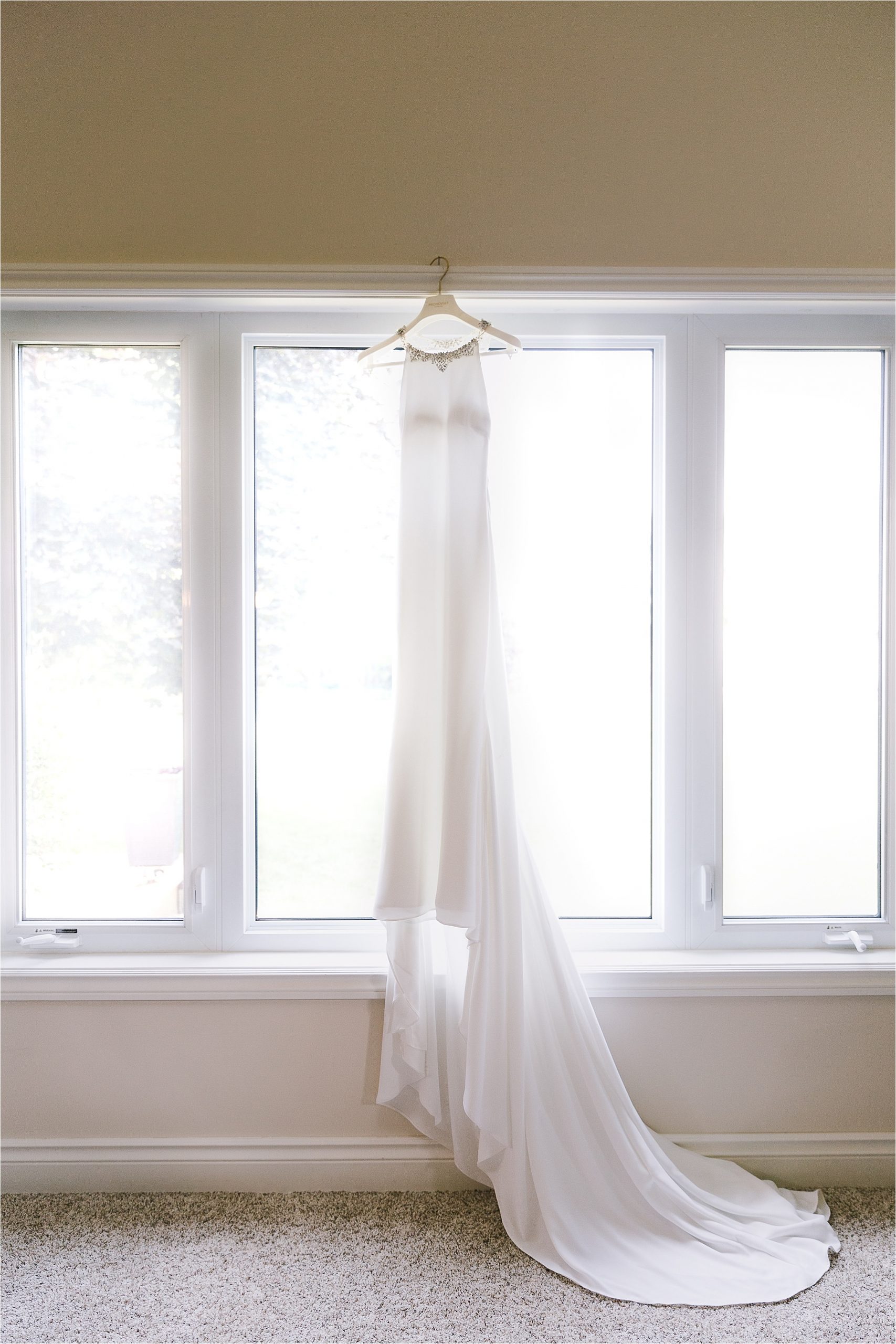 Bridal gown wedding dress from Provonias hanging in front of window
