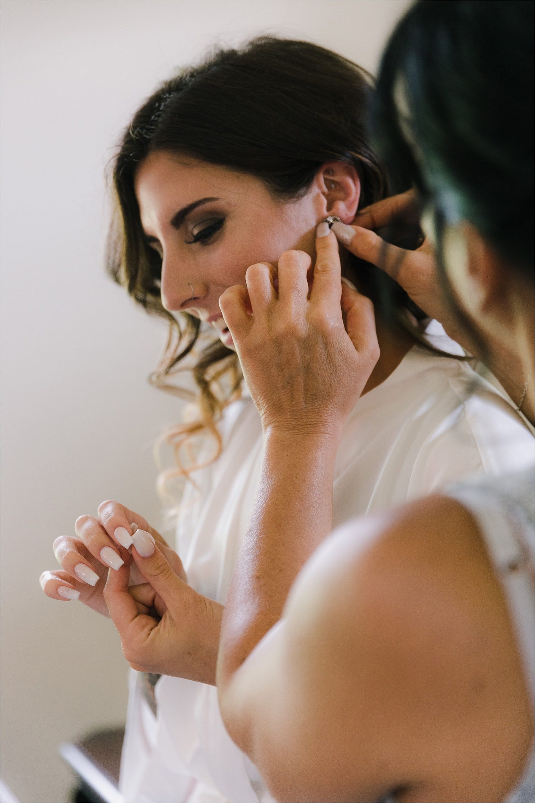Mother of the bride putting in earrings for bride