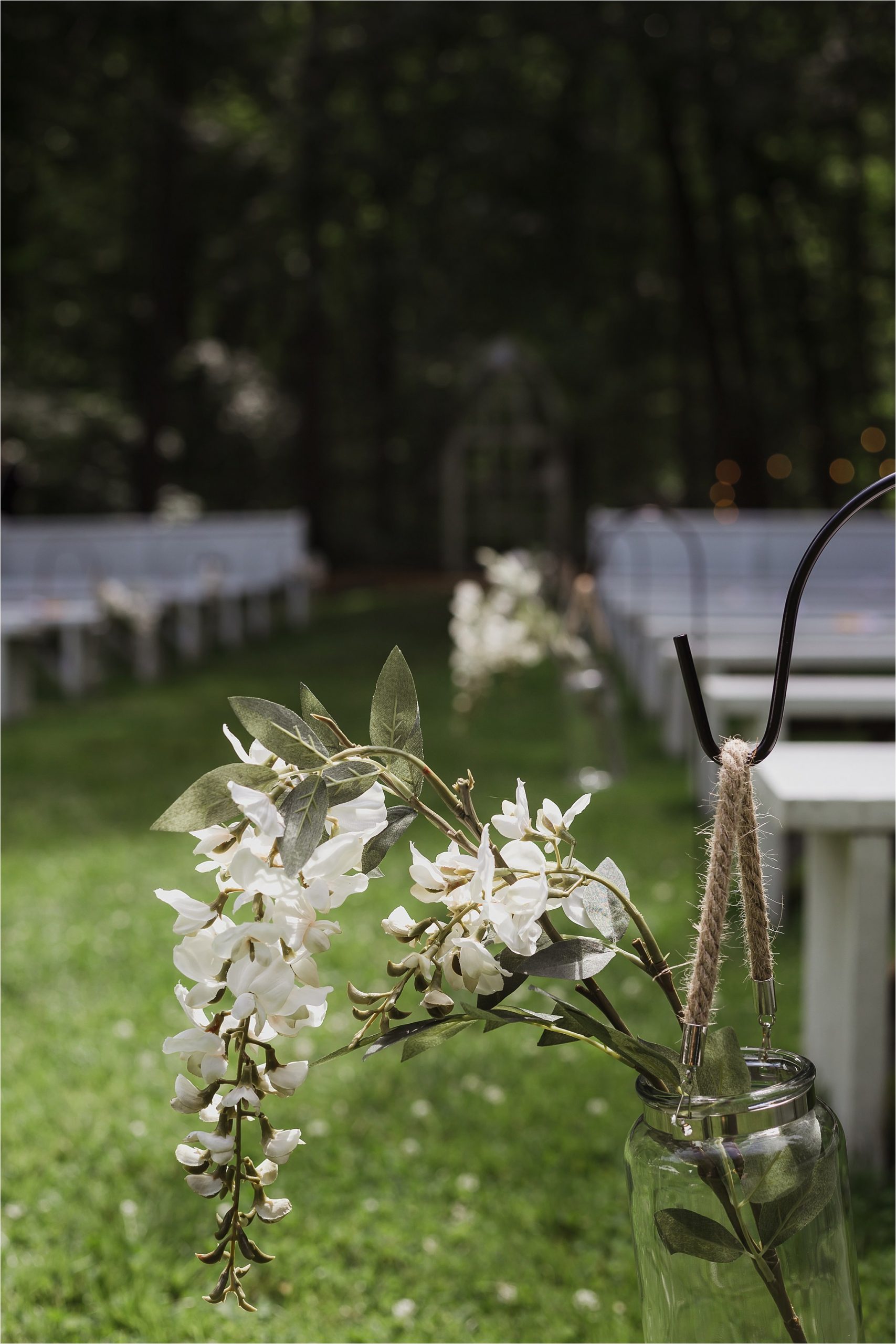 The Clearing wedding venue ceremony decoration with benches and floral mason jar arrangements