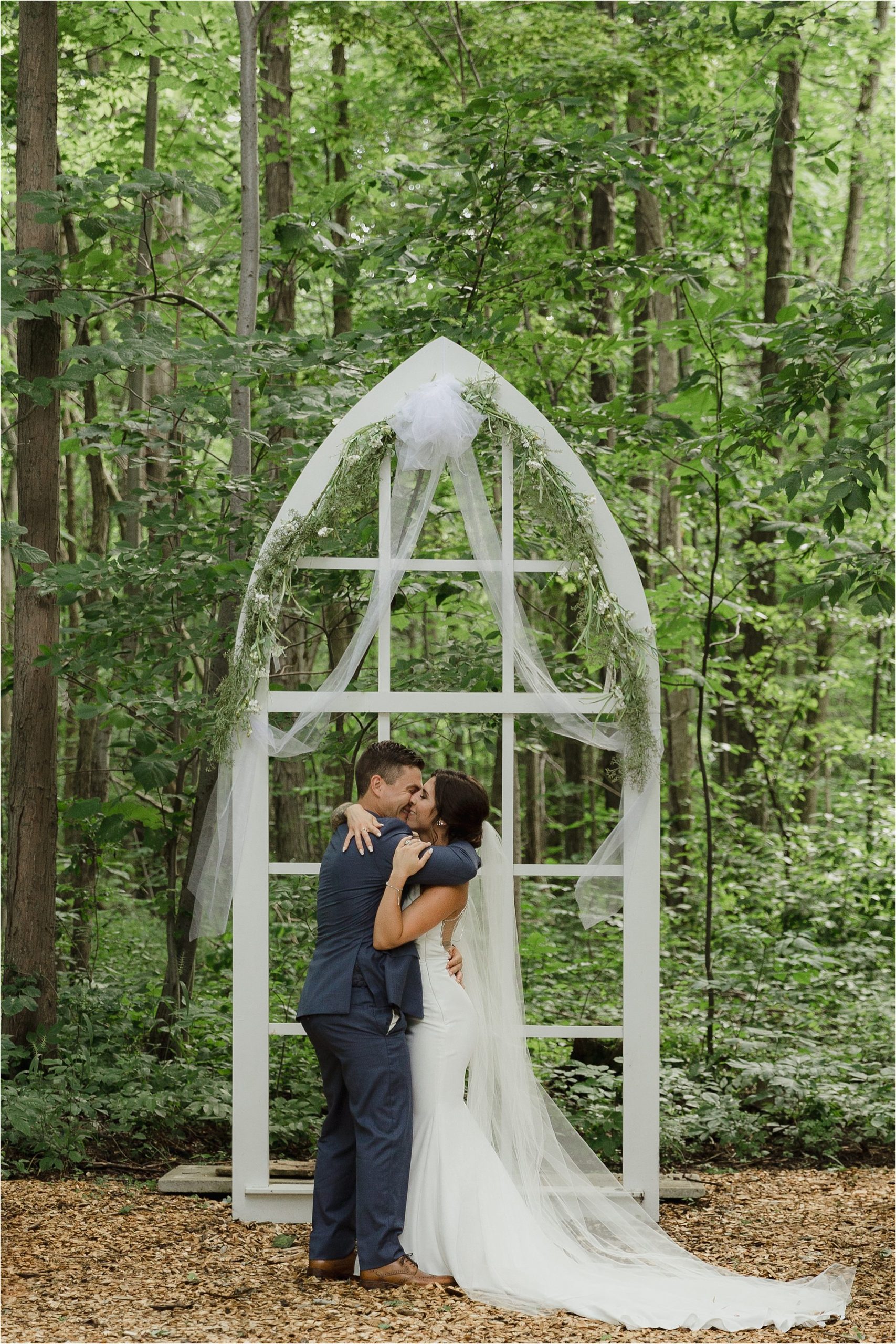 The Clearing ceremony wedding venue bride and groom first kiss in front of arbor