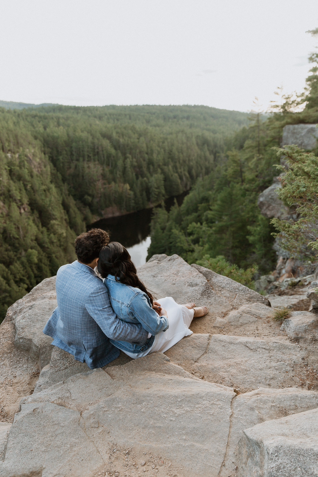 Mrs. Jacket by Revelle bride and groom sitting on the edge of a cliff at Barron Canyon in Algonquin Park after their elopement - Sonia V Photo -Documentary Style Candid Photographer - Ottawa Ontario Kemptville Destination Photographer - Authentic Colour Photography - Wedding Photographer - Branding Photographer - Small Business Headshots - Engagement Photos - Family Portraits - Lifestyle