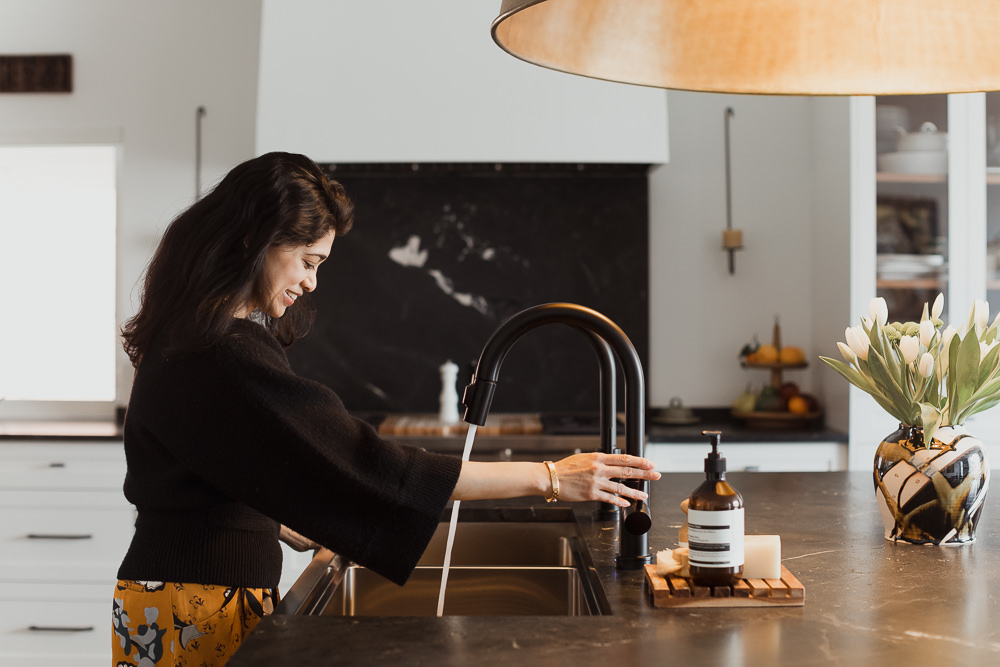 woman standing at sink kitchen with large brass fixture home in the Glebe Ottawa Ontario Studio-Kahaani-Ottawa-interior-design-inspiration-ideas-brand-photos-by-Sonia-V-Photography