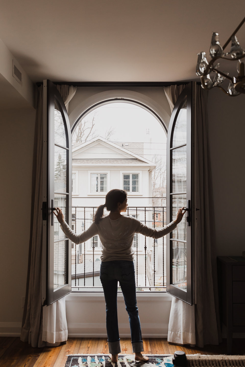 woman standing in french windows opening doors to veranda in bedroom Indian inspired home in the Glebe Ottawa Ontario Studio-Kahaani-Ottawa-interior-design-inspiration-ideas-brand-photos-by-Sonia-V-Photography