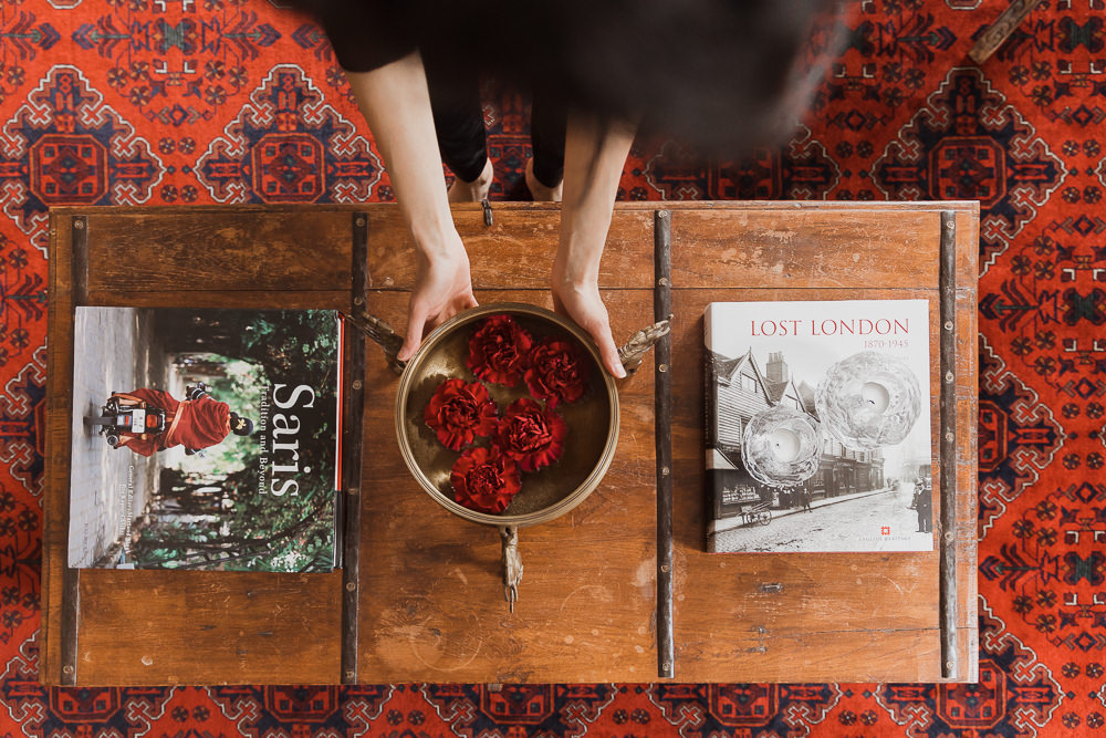 woman holding brass dish with red carnations over wood table and persian rug Studio-Kahaani-Ottawa-interior-design-inspiration-ideas-brand-photos-by-Sonia-V-Photography