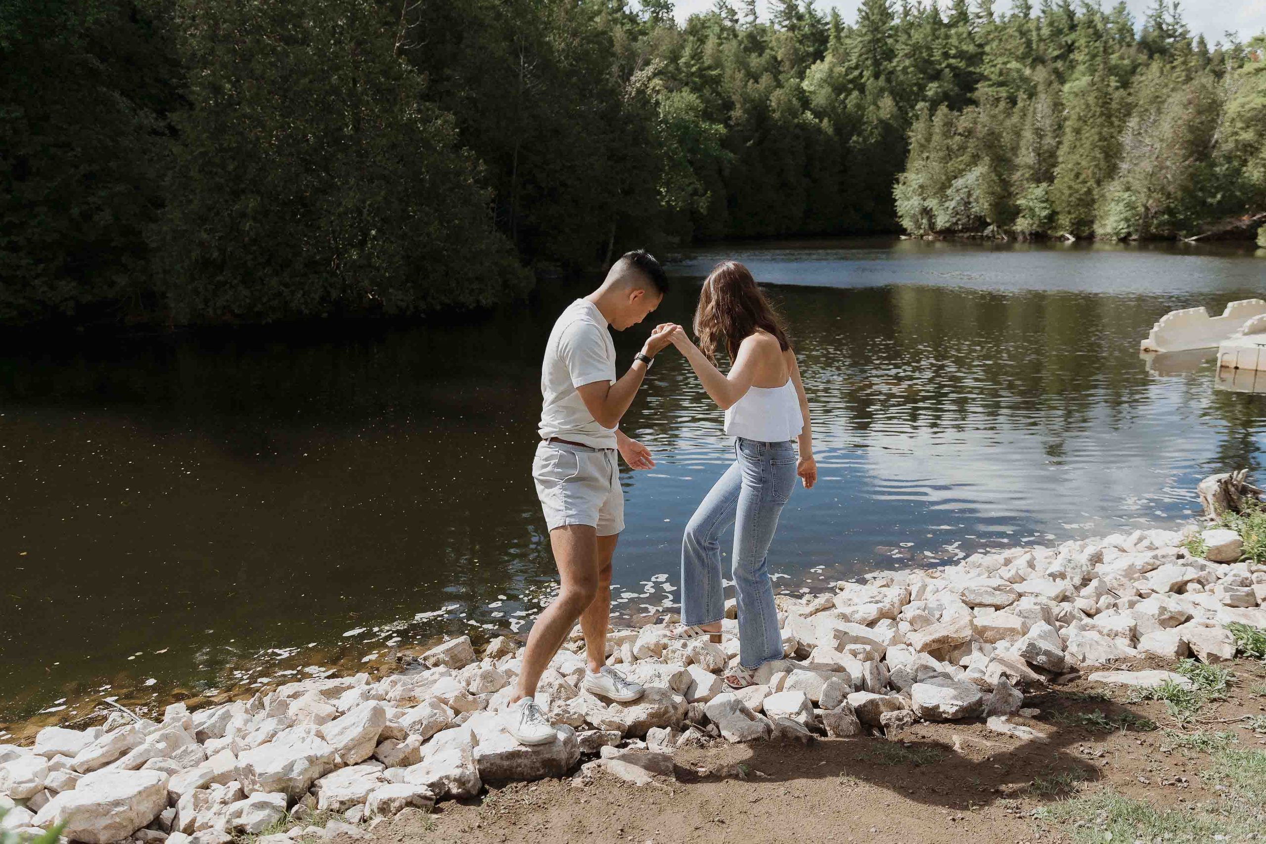 Engagement photos at Guelph conservation area, guelph lake, harris mill ruins, Sonia V Photography couple walking on rocks in front of lake trees water