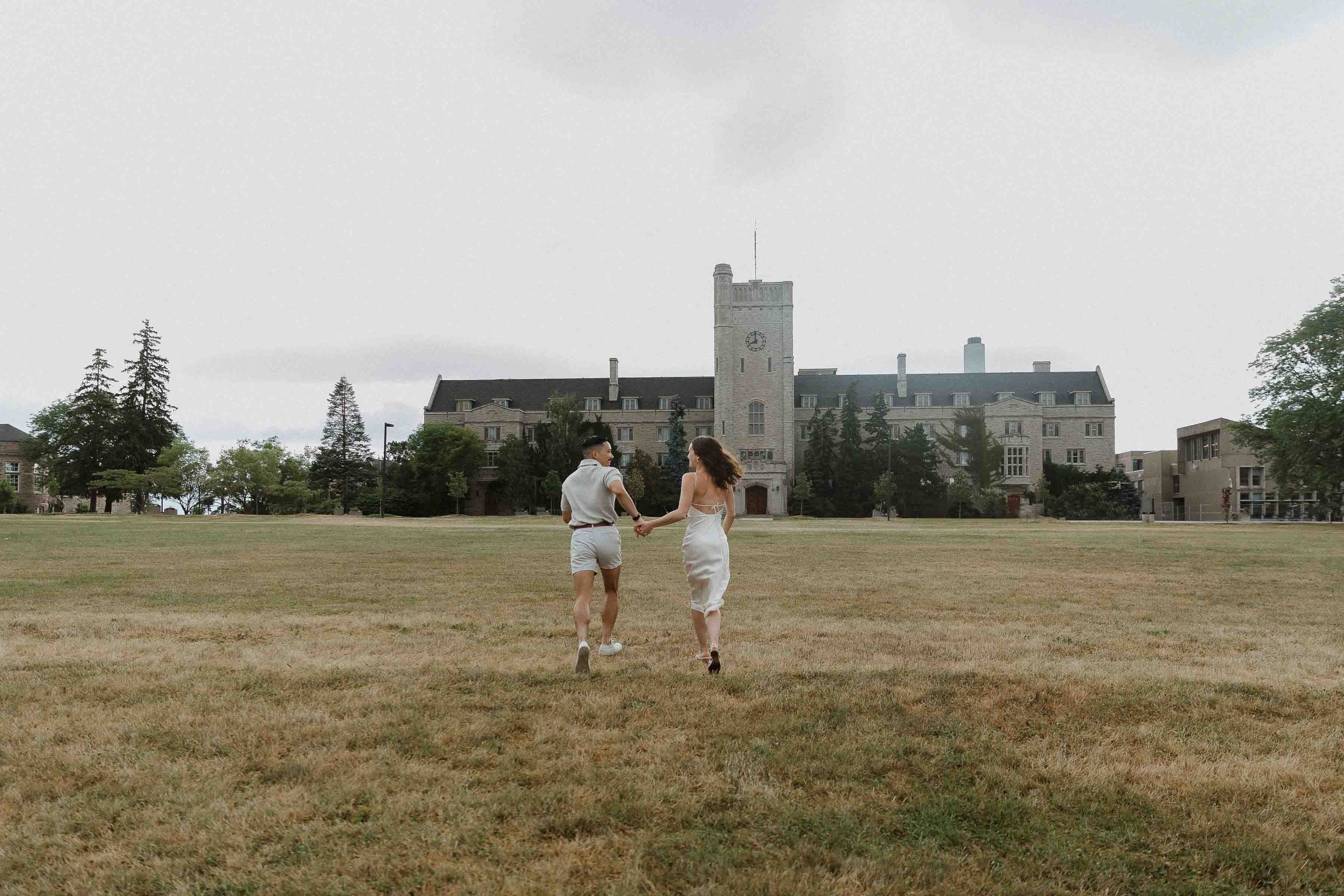 Engagement photos at Guelph University outside the old buildings | Sonia V Photography couple running through university field