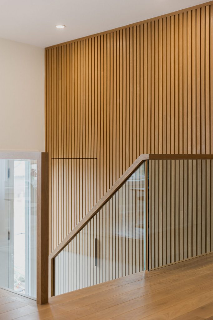 Unique all glass entry staircase railing by VI Design Ottawa and Murdock Construction and wood slatted feature wall