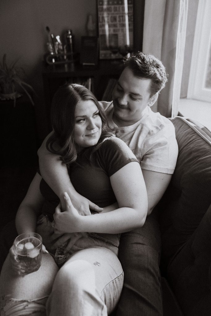 Couple sitting on the couch in orange living room retro style interiors in their home in rural Ontario, in-home engagement photos by Sonia V Photography